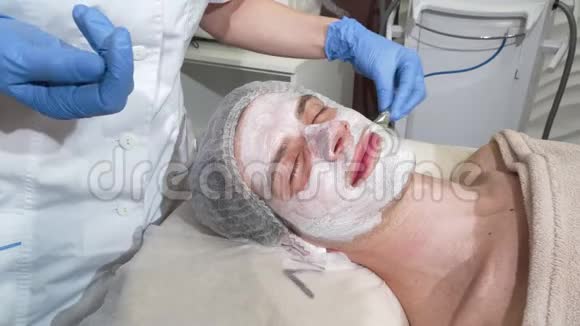 快乐的男人在美容院戴着面具闭着眼睛微笑视频的预览图