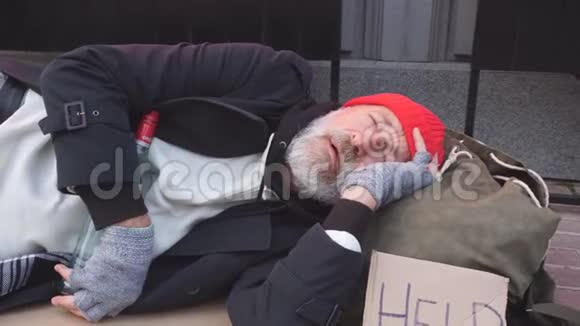 可怜的乞丐穿着旧衣服躺在纸板箱里视频的预览图