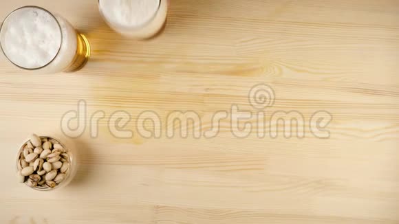 新鲜啤酒手把一瓶美味的啤酒放在杯子里靠近其他杯子和碟放在背景的木桌上视频的预览图