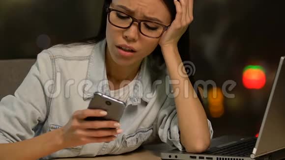 极度疲惫的自由职业女性滚动电话躺在笔记本电脑上没有精力视频的预览图
