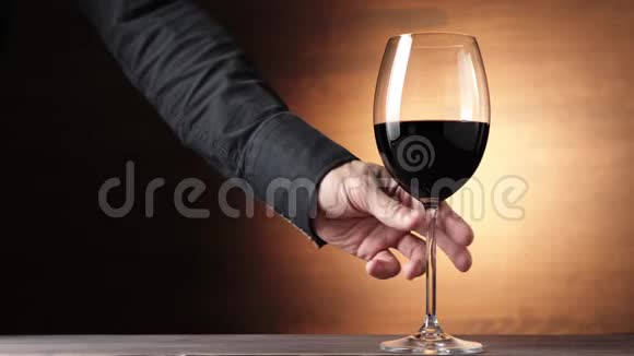 豪华红酒手拿着一个酒杯在棕色背景下从桌子上拿出美味的葡萄酒玫瑰酒视频的预览图