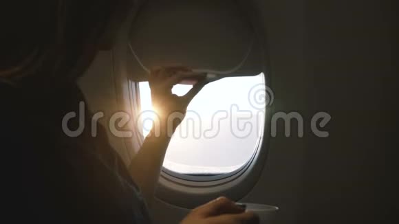 近距离拍摄快乐的乘客女性打开飞机窗口享受饮料和美丽的阳光景观在飞行视频的预览图