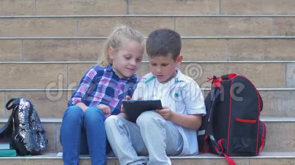现代的小学生在课间休息时在学校的台阶上使用背包的小工具视频的预览图
