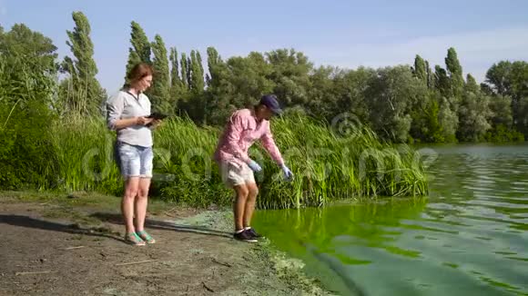 生态学家小组在污染河流沿岸采集绿藻样本视频的预览图