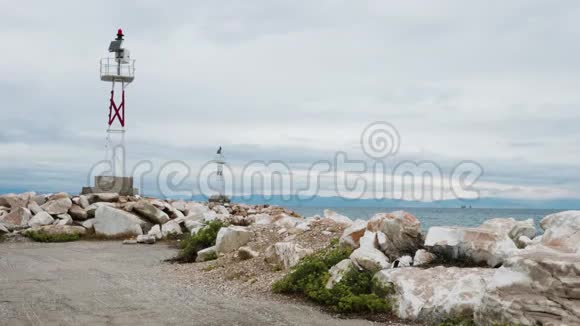 岩石海滩上的小灯塔和平静的海水视频的预览图