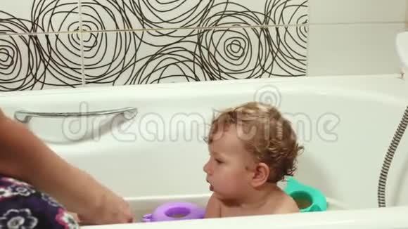 那孩子和妈妈在浴室洗澡玩玩具一个蓝眼睛的婴儿头发是金色的带玩具视频的预览图