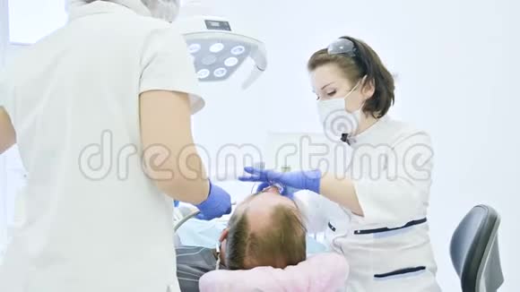 女牙医带着助手检查病人一个老人的嘴高级关键专业工作视频的预览图