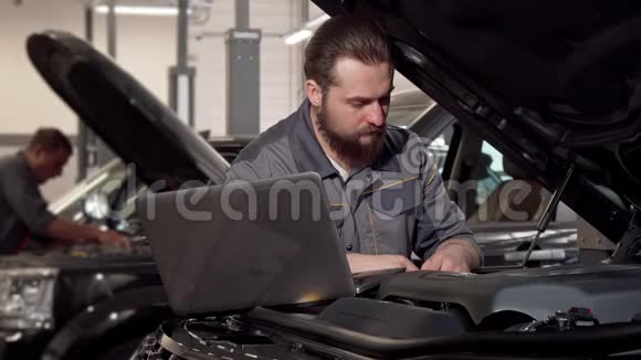 汽车服务人员使用笔记本电脑检查汽车发动机视频的预览图