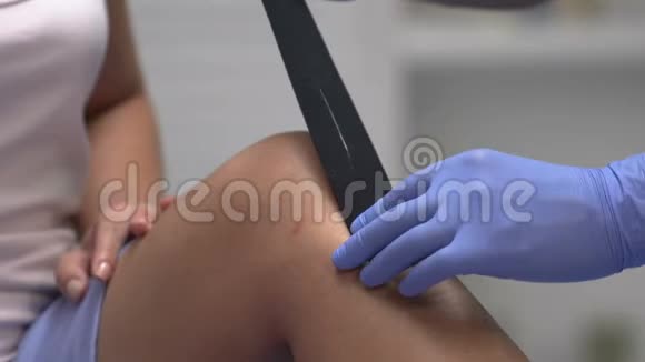运动医生给疼痛的病人膝盖贴带子创伤康复视频的预览图