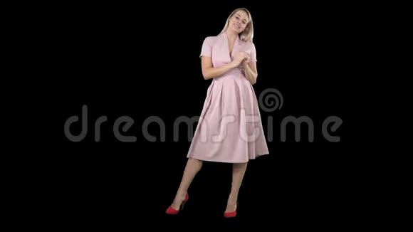 快乐的金发女郎穿着粉色衣服对着镜头指着侧面阿尔法频道视频的预览图