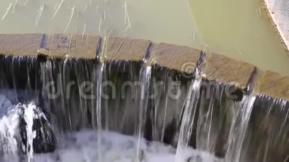 池塘里的水从栅栏的混凝土墙上倾泻下来视频的预览图