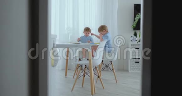 年轻的妈妈和两个儿子24岁的孩子在坐在客厅桌子旁的布玛拉铅笔视频的预览图