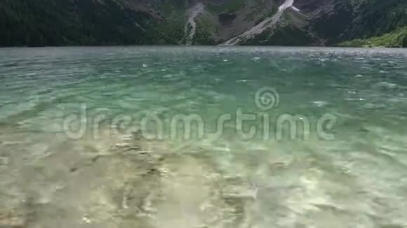 美丽的湖泊清澈透明的水在群山之间阳光和海浪的眩光视频的预览图