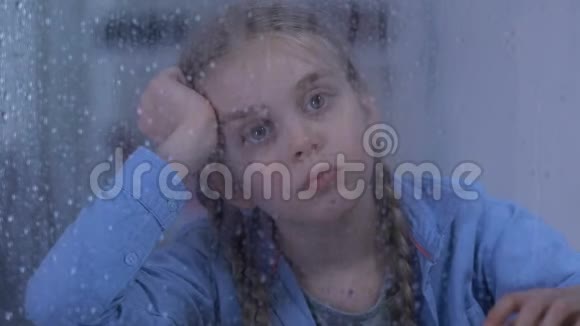 悲伤的孤儿女孩看着雨夫妇站在后面寄养家庭来了视频的预览图