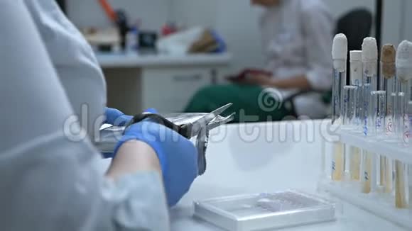 实验室里的一位女化学家打开一个装有剪刀的包裹里面有一个微板供研究使用反病毒视频的预览图