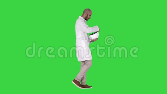科学工程师在绿色屏幕上行走和戴上安全概念头盔Chroma键视频的预览图