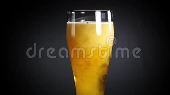 啤酒倒在黑色背景上的玻璃杯里琥珀啤酒诱人地倒入啤酒杯视频的预览图