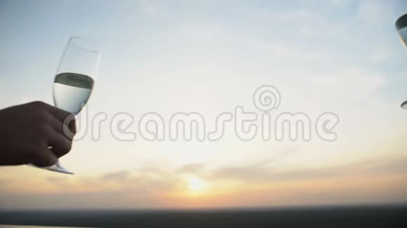 一对情侣在夕阳的背景下碰着香槟酒杯浪漫的约会视频的预览图