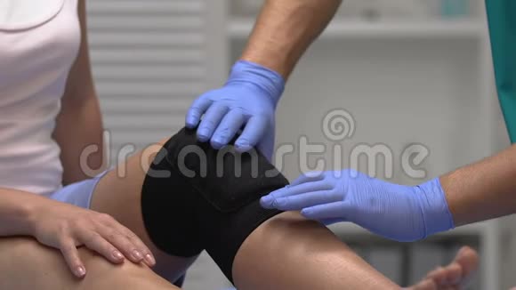 治疗师用压膝支架触摸病人腿部创伤康复视频的预览图