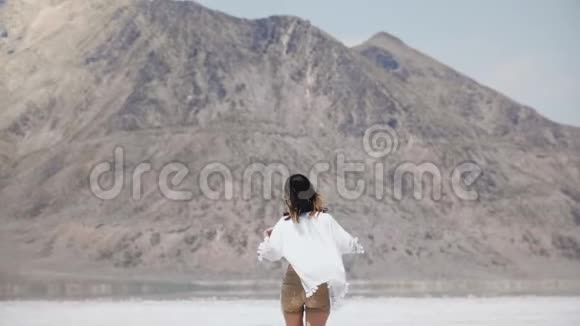 镜头跟随年轻快乐的自由女人走向山手臂张开飞扬的头发在盐湖犹他州视频的预览图