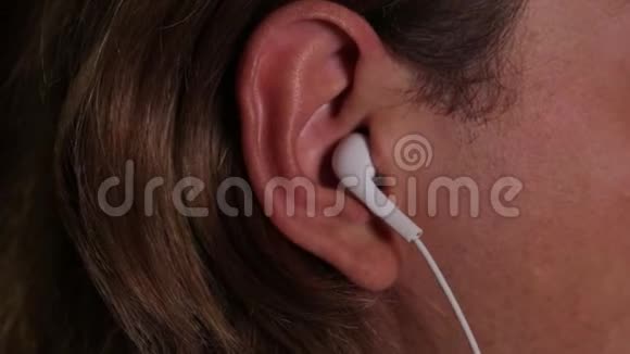 一个金发的年轻人从耳朵里拿出耳机耳朵的特写视频的预览图