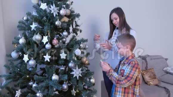 妈妈和儿子一起在家客厅装饰人造圣诞树视频的预览图