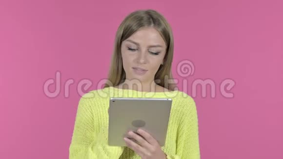粉红背景下的小女孩用平板和微笑视频的预览图