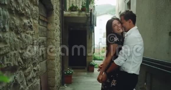 有魅力的年轻夫妇带着大大的微笑在意大利的一条小老街中间度过了一段浪漫的时光视频的预览图