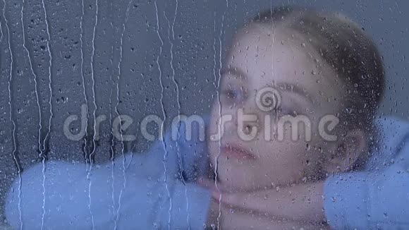 伤心的女孩望着窗外的雨滴梦见孤儿院里的家人视频的预览图