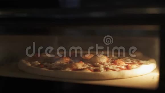 在烤箱里烤奶酪披萨的手持近景视频的预览图