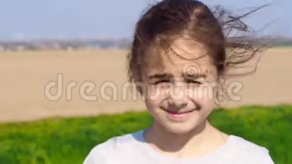 美丽的年轻女孩在户外寻找头发在大自然的背景下吹着视频的预览图
