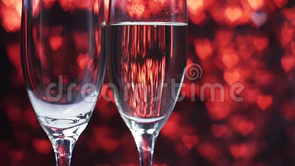 香槟被倒入一个红色背景上的玻璃杯中里面有许多心靠近视频的预览图