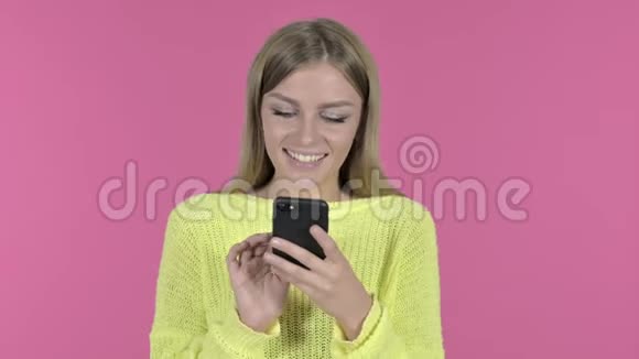 使用智能手机的快乐少女粉红背景视频的预览图