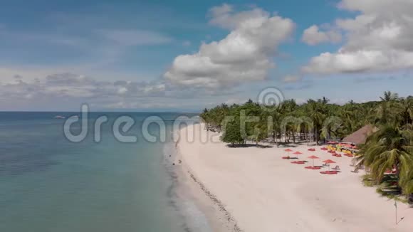 空中电影无人机拍摄的白色空沙滩红色雨伞和干净平静的蓝海或海洋与船视频的预览图