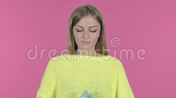 年轻漂亮的女孩手里拿着模型房粉色背景视频的预览图