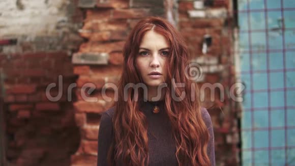 一个红发女孩的特写肖像带着神秘的表情有雀斑的女孩看着相机头发随风飘扬视频的预览图