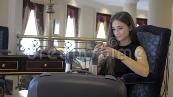 年轻女孩在酒店里看电话留言直到等她的房间视频的预览图