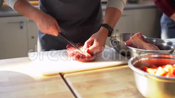 穿灰色围裙的厨师在塑料板上切肉烹饪过程的特写照片视频的预览图