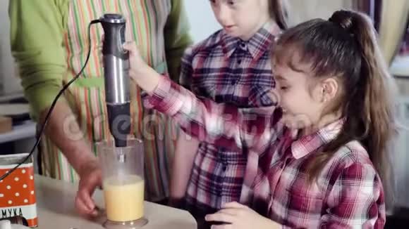 家庭的快乐父亲和女儿一起用厨房搅拌机准备晚餐视频的预览图