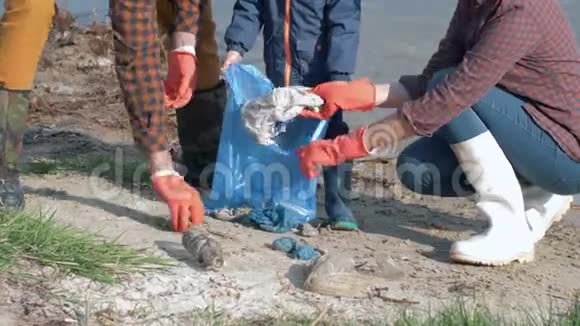 把地球从塑料中拯救出来年轻的家庭志愿者带着戴着橡胶手套的孩子在打扫卫生的时候把垃圾收集到垃圾袋里视频的预览图