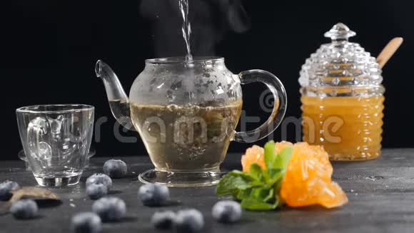 茶叶酿造仪式绿色中国茶花玻璃茶点在木制背景蓝莓蜂蜜玻璃罐视频的预览图