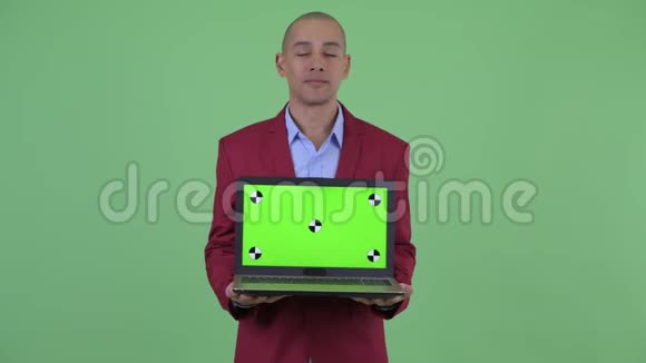 快乐的秃头多民族商人一边看笔记本电脑一边说话视频的预览图