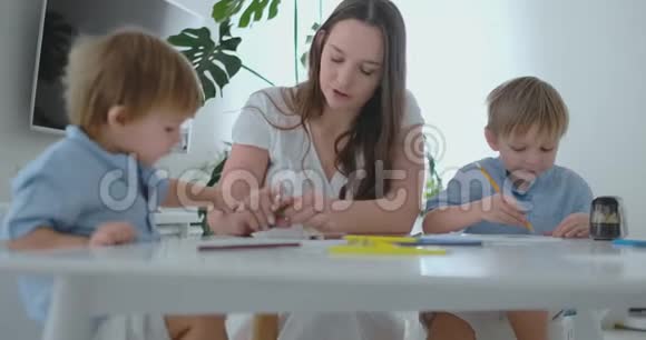 妈妈帮助两个2岁和4岁的儿子做学前作业用铅笔画画视频的预览图