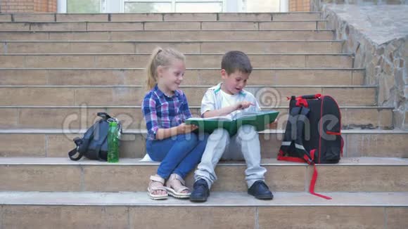 学校里的友谊小同学带着背包坐在台阶上休息时在新鲜空气中看书视频的预览图