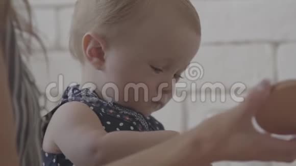 在母亲帮助她的时候孩子正在玩麦片粥厨房里的年轻女人带着她的孩子视频的预览图