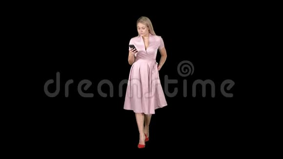 穿着粉色衣服的年轻女子在走路时看着手机发短信阿尔法频道视频的预览图