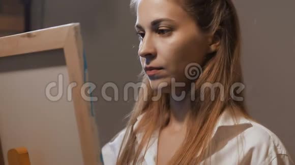 艺术家的肖像女孩站在画架上画了一幅画她很感兴趣4K慢慢视频的预览图