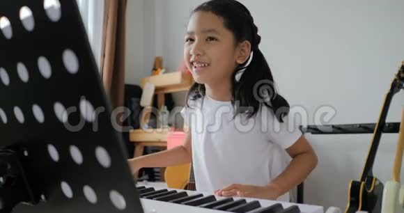 亚洲小女孩学习基本钢琴使用电动合成键盘初学者音乐器乐自学视频的预览图