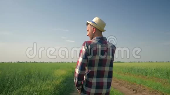 戴着帽子和格子衬衫的男农在手机上交谈时享受新鲜空气和大自然的美丽视频的预览图
