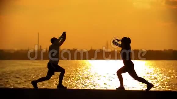 在海滨训练前一对夫妇揉捏腿部肌肉的黑暗轮廓视频的预览图